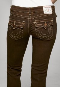 Hnědé džíny z denimu s přiléhavým střihem, s bílým šitím a vyšívanými zadními kapsami, viditelná značená štítek na pásku.