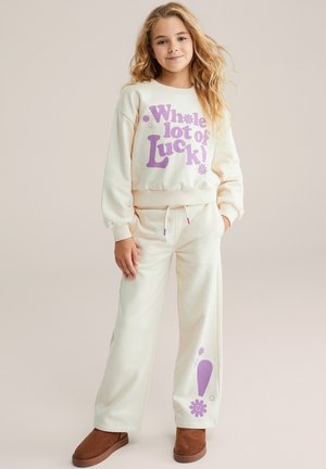 Sudadera color crema y pantalones a juego con texto gráfico en púrpura "¡Mucha suerte!" y diseños florales. Tela suave, ajuste relajado.