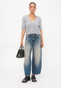  Lichtgrijze, kortwaardige cardigan met ronde knopen en parelaccenten, gecombineerd met high-waisted, wijde, vervaagde blauwe denimjeans en zwarte platform loafers.
