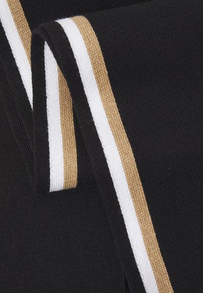 Tissu en tricot noir avec des rayures horizontales blanches et dorées. La texture est lisse, avec une qualité douce et extensible. Présente un bord effilé.