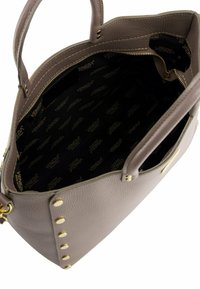 Grijze leren handtas met gouden hardware en studs, met een gevoerd interieur dat een ritsvak en een logo-patroon bevat.