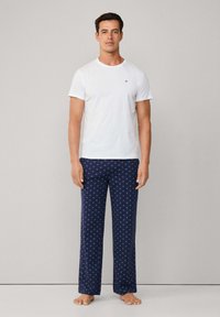 Bílý tričko s krátkým rukávem a kulatým výstřihem, doplněné námořnicko-modrými pyžamovými kalhotami se vzorem hvězdiček. Volný střih, jednoduché a vzorované textilie.