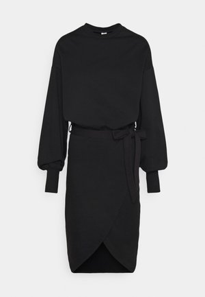 Schwarzes langärmeliges Midikleid mit hohem Halsausschnitt, Puffärmeln, eng anliegenden Bündchen, Wickelrock und gebundenem Taillengürtel auf weißem Hintergrund.