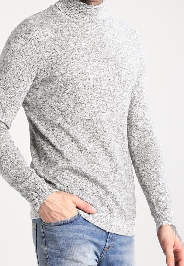 Pull à col roulé gris en tricot texturé, coupe ajustée, manches longues et ourlet arrondi, porté avec un jean bleu.
