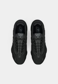 Black athletic shoes with a textured mesh upper, streamlined design, and contrasting lacing system. Features logos on the tongues and sides.