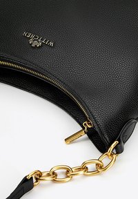 Borsa in pelle nera con texture a granuli, zip dorata e manico a catena. Presenta un'etichetta con marchio e un design piegato all'apertura.