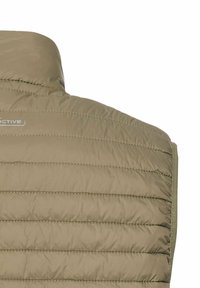 Gros plan de l'arrière d'une veste matelassée marron clair avec des coutures horizontales et un col montant.