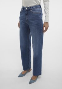 Hoch taillierte, gerade geschnittene blaue Jeans aus Denim mit leichter Ausbleichung. Sie verfügen über Vordertaschen, einen einzigen Knopfverschluss und kontrastierende Nähte.
