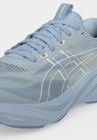 Ανοιχτό μπλε παπούτσι για τρέξιμο Asics με επάνω μέρος από διχτυωτό υλικό, επενδεδυμένο γιακά, παχιά σόλα και λευκές λωρίδες λογοτύπου στο πλάι.