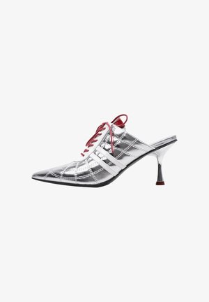 Zapatilla mule plateada de tacón alto y punta afilada, con cordones rojos y franjas blancas laterales, con un patrón acolchado y tacón delgado y curvado.