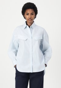 Camicia a righe blu chiaro e bianco, con bottoni, due tasche sul petto, colletto e vestibilità morbida. Realizzata in tessuto morbido, con maniche lunghe.