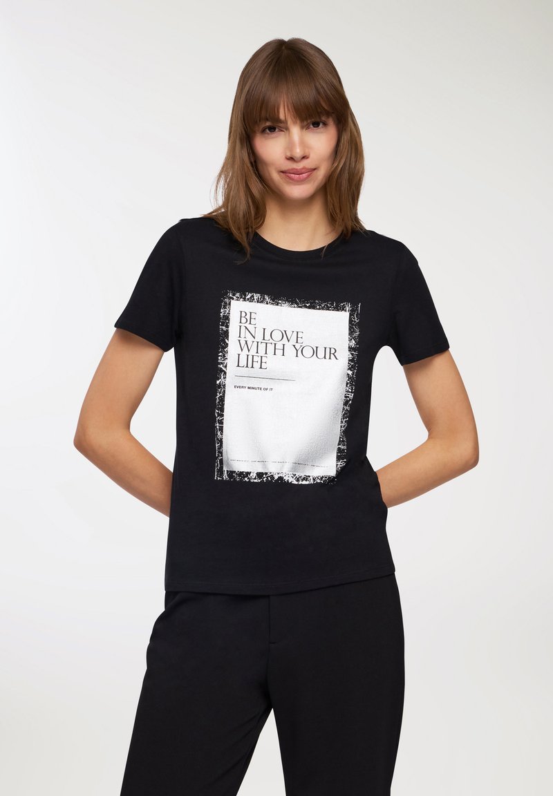 T-shirt in cotone nero con una grafica centrata che riporta il testo "AMA LA TUA VITA" in bianco e un bordo rettangolare in stile usurato.