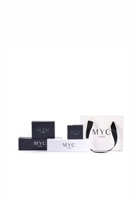Collection de boîtes cadeaux et d'un sac fourre-tout. Les boîtes sont bleu marine et blanches avec un logo embossé "MYC PARIS", de tailles variées, texture mate. Poignées noires sur le sac.