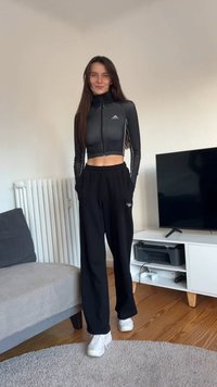 Black athletic cropped zip-up jacket with long sleeves paired with loose black sweatpants. White sneakers complete the outfit.