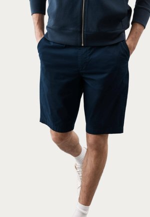 Marineblauwe shorts van lichtgewicht stof, met een rechte snit en zijzakken, gecombineerd met witte sokken en lichte sneakers.