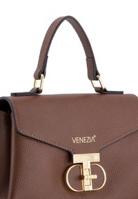Braune Lederhandtasche mit strukturierter Oberfläche, goldenen Beschlägen, einer definierten Form und einem eleganten oberen Griff. Mit einem eingestanzt Logo auf der Vorderseite.