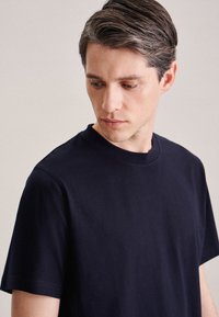 T-shirt di cotone blu navy con collo a giro e maniche corte. Texture liscia senza motivi o dettagli hardware visibili.