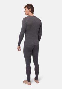Grå långärmad termotopp och matchande leggings med strukturerad yta, med en tät passform och sömlös konstruktion, barfota.