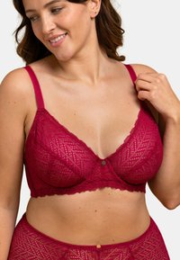 Bralette en dentelle de couleur bourgogne profond avec un motif géométrique, des bretelles réglables et un détail central de bouton décoratif. Fini doux et texturé.
