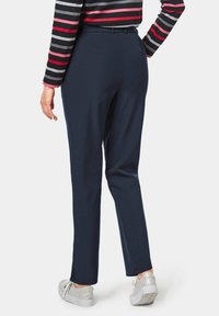 Marineblauwe broek met een soepele textuur, rechte snit en riemlussen. Gekocht met zilveren sneakers, die een subtiele glans hebben.