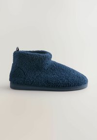 Pantofole da interno in pile di colore blu navy con bordo alto alla caviglia e suola in gomma nera, progettate per calore e comfort.