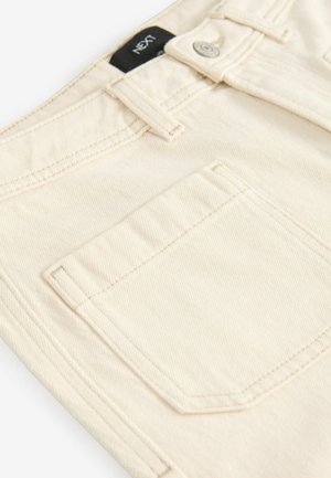 Beige pamut nadrág, klasszikus szabásban, elülső gombos záródással, látható varratokkal és egy hátsó zsebbel. Márkajelzés a derékvonalon.