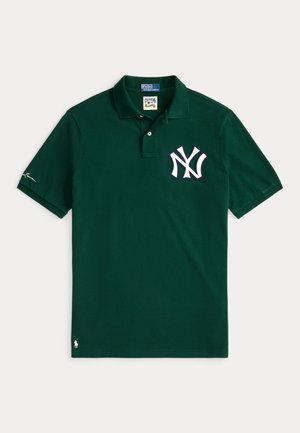 Tume roheline polo-särk, mis on valmistatud puuvillast, vasakpoolsel rinnal valge tikandiga New York Yankeesi logo ja väikese logoga varrukal.
