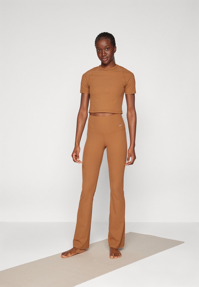 Set di abbigliamento attivo marrone con t-shirt cropped e leggings a zampa. Tessuto liscio con design aderente e logo sul cinturino.