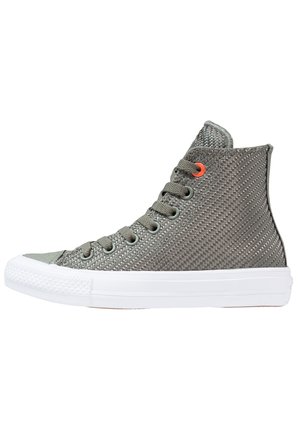 Wysoki sneaker z teksturowanego szarego materiału z szarymi sznurówkami, białą gumową podeszwą i jednym pomarańczowym oczkiem blisko góry.