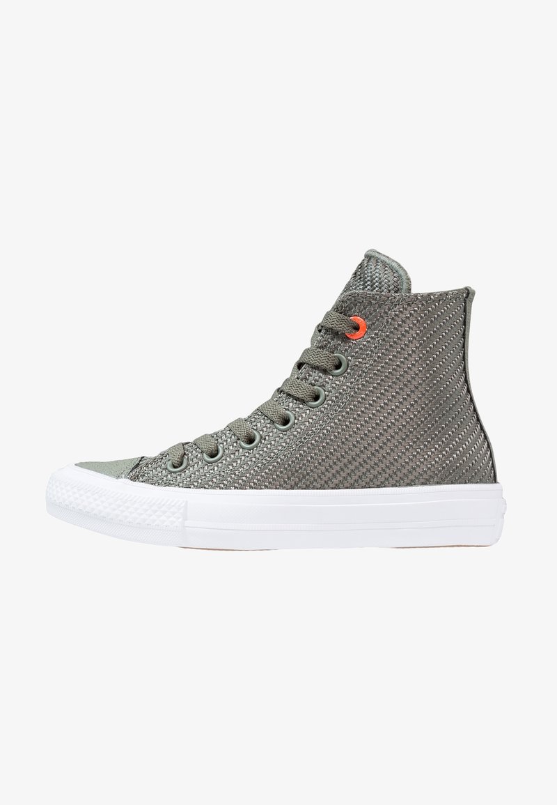 Basket montante en tissu gris texturé avec lacets gris, semelle en caoutchouc blanche et un œillet orange près du haut.