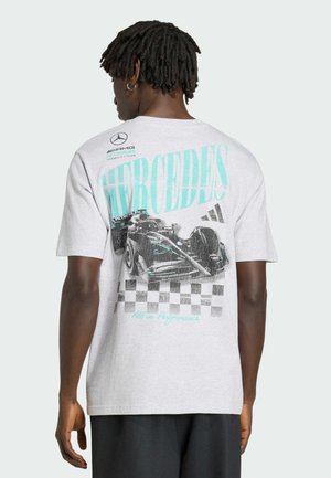 Mand iført grå Mercedes AMG Petronas Formel 1 T-shirt med et racerbilsdesign, ternet mønster og logoer på bagsiden.