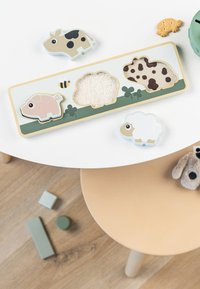 Puzzle en bois représentant des animaux avec un cochon rose clair, une vache brune, un mouton blanc et des éléments texturés. Présente des formes arrondies et des couleurs pastel.