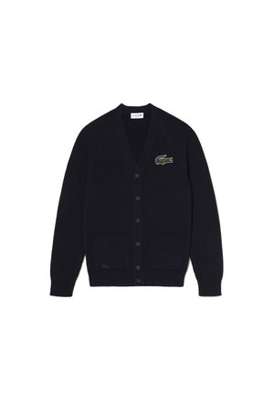 Cardigan noir en maille côtelée avec col en V, fermeture par boutons, deux poches avant et un logo crocodile vert sur la poitrine gauche.