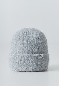 Gray knitted beanie hat with a soft, textured finish. Features a folded cuff and a small branded logo tag on the side.