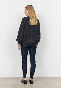 Pullover a maglia testurizzata grigio scuro con maniche a palloncino, abbinato a jeans skinny neri e mocassini neri, visto da dietro.