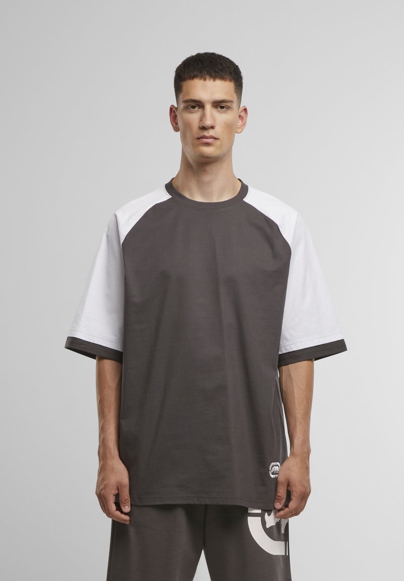 Grijs en wit t-shirt met korte mouwen, met een ronde hals, raglanmouwen en subtiele logodetails bij de zoom. Zacht katoenmateriaal.
