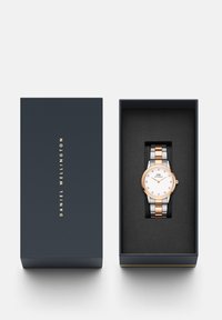 Daniel Wellington pulkstenis zila kastē. Apaļa balta ciparnīca, rozā zelta korpuss, sudraba un melna siksna ar savienojamām saitēm. Melnā iekša.