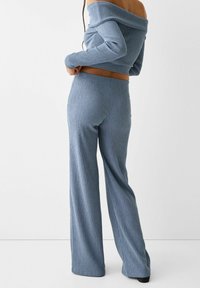 Lichtblauw geribbeld twee-delig set bestaande uit een off-shoulder crop top en wijde broekspijpen, met een gladde textuur en een aansluitende tailleband.