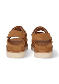 Sandalias de ante color marrón con dos correas ajustables de Velcro. Cuentan con una suela blanca acolchada y una plantilla texturizada para mayor comodidad.