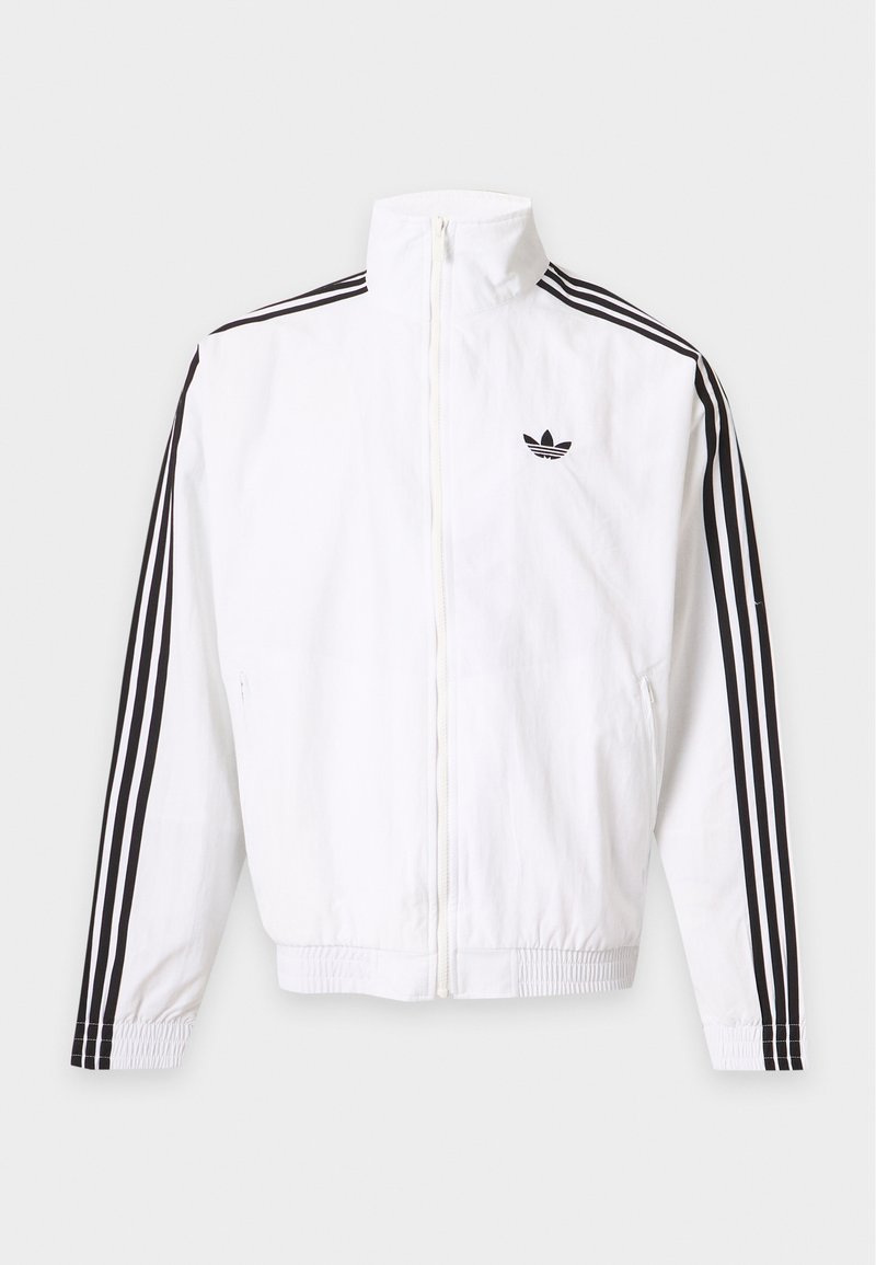 Hvid lynlåsjakke med sorte striber ned ad ærmerne og et sort Adidas-logo på venstre bryst.