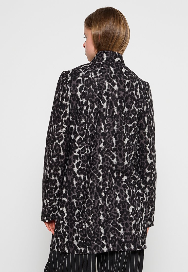 Manteau en imprimé léopard noir et gris, avec une silhouette structurée, des manches longues et un col montant. Tissu doux avec une finition texturée.