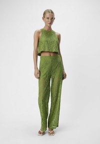 Conjunto de top corto de encaje verde y pantalones, con un diseño en capas, intrincados patrones florales y un ajuste holgado. Tejido texturizado y semitransparente.