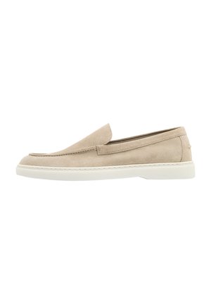 Mocassin beige en daim sans lacets avec semelle en caoutchouc blanche et détails cousus, présenté de profil sur fond blanc.