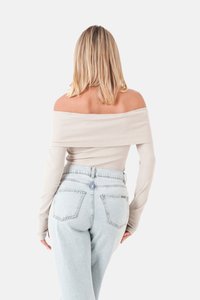 Hellbeige gestreiftes Top mit schulterfreiem Design und langen Ärmeln, kombiniert mit hochgeschnittenen, hellblauen Jeans. Schlichtes, tailliertes Design.