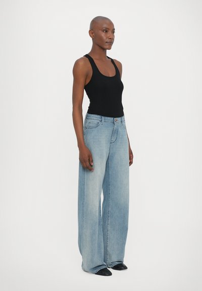 Ljusblå vida jeans med hög midja, i kombination med en åtsittande svart tanktop. Jeansen har två framfickor och en knappstängning.