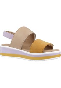 Sandale en cuir marron et jaune avec un petit talon compensé, ouverte à l'avant et avec une bride à la cheville. Présente une semelle en plateforme violette et blanche.