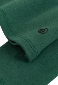 Grüner Baumwollstoff mit einer glatten Textur, der ein dezentes Logo in Schwarz aufweist. Die Nähte sind sauber in passendem Grün abgeschlossen.