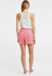 Haut gris sans manches avec un dos en dentelle, associé à un short fleuri rouge. Tissu en coton, coupe décontractée, motif floral blanc sur le short.