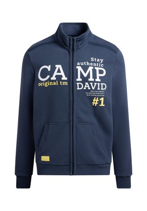 Marineblaue Sweatjacke aus weichem Stoff mit Stehkragen und Reißverschluss. Mit bedrucktem Text in Weiß, Gelb und Schwarz. Zwei Vordertaschen.