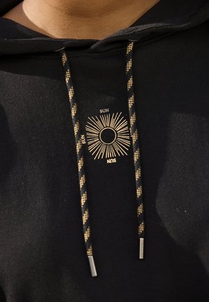 Black hooded sweatshirt featuring gold sun graphic and text “SUN.” Thick drawstrings with a braided pattern and metallic tips.